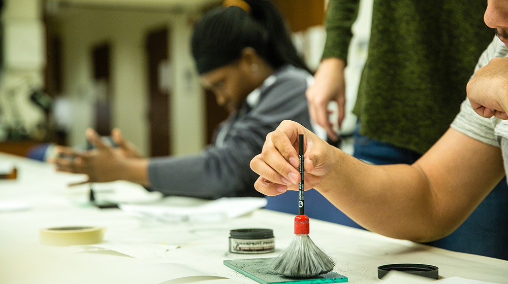 A close up view of a person holding a brush over a latent print.