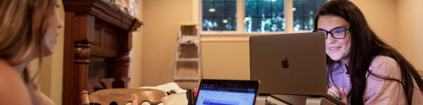 Two Loyola students study at a table as they study on their laptops