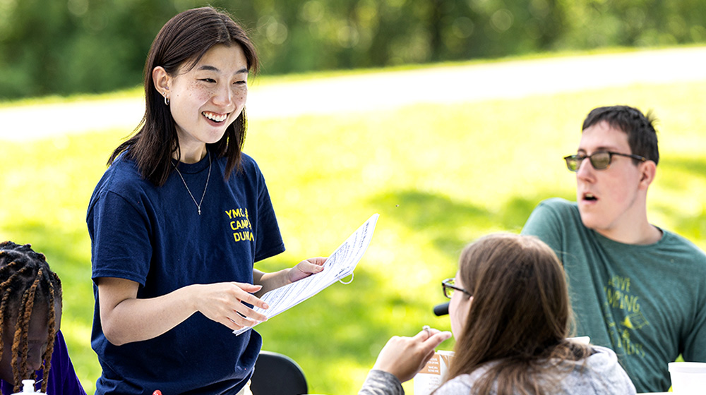 Loyola post-baccalaureate student Esther Yun stands at a table with other volunteers and attendees as she hosts a workshop with Camp Independence.